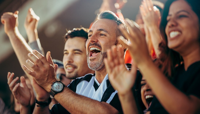 Football fans enthusiastically cheering at a stadium.