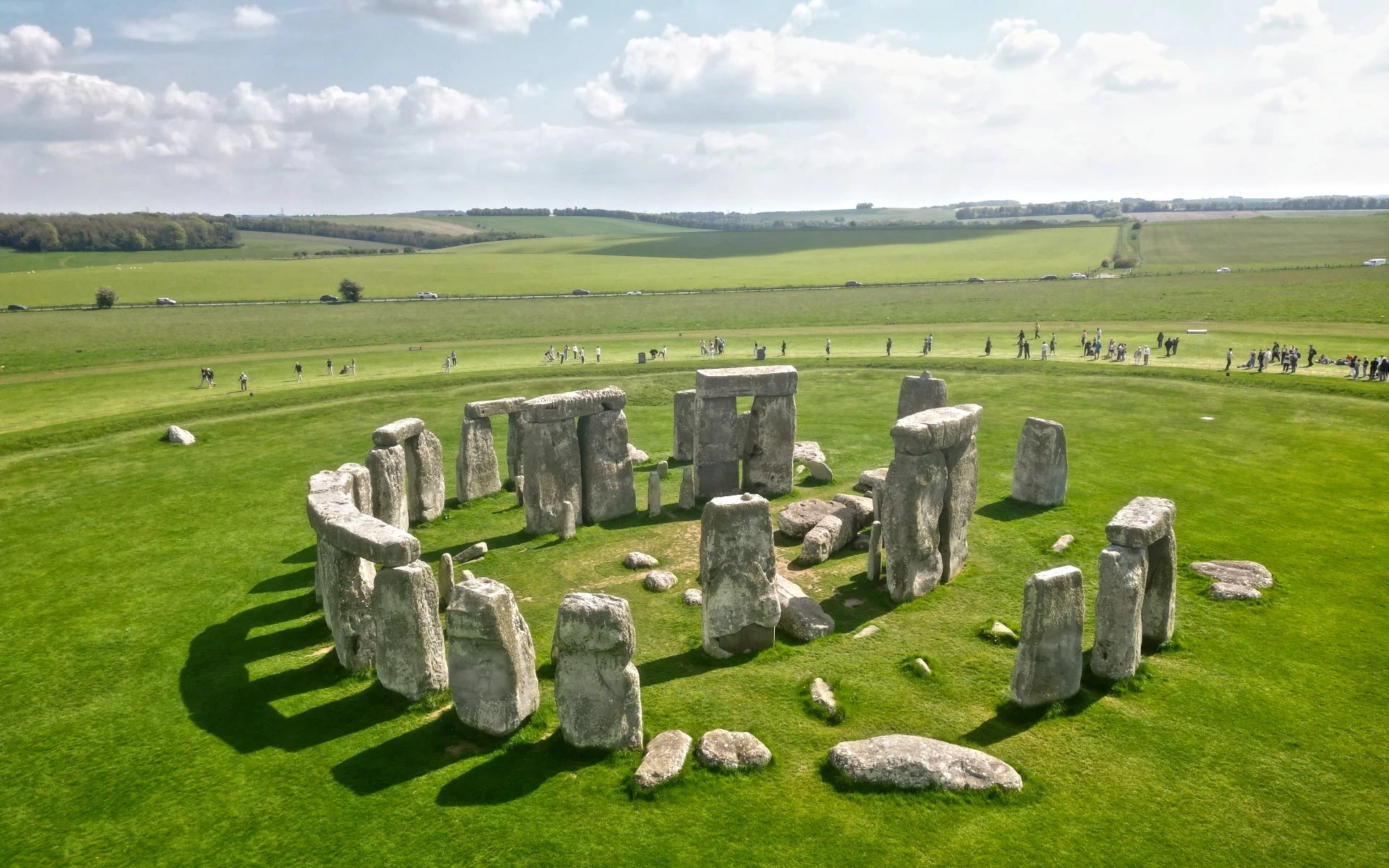Stonehenge stone circle on a grassy plain with tourists in the background.