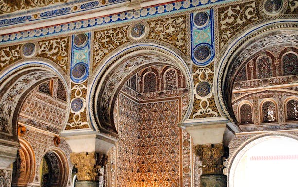Intricate Moorish arches and detailed tilework in Alcazar Seville interior.