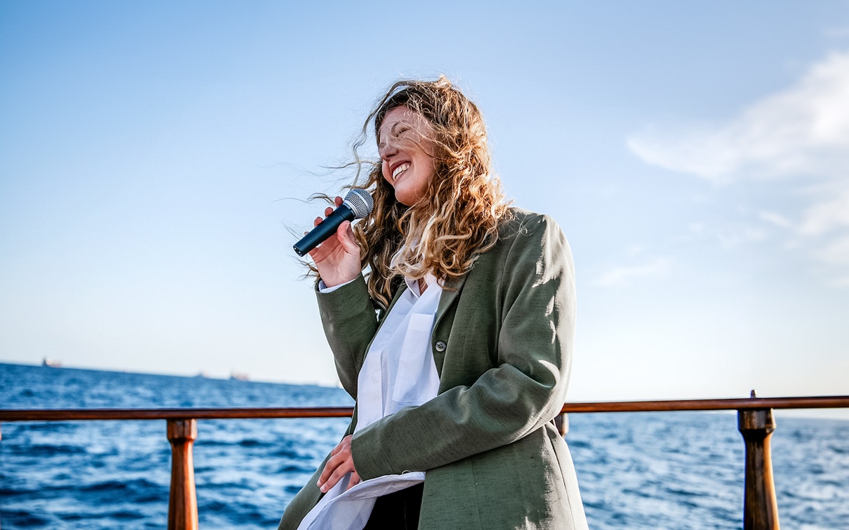 Person singing on a catamaran in Barcelona with ocean view.