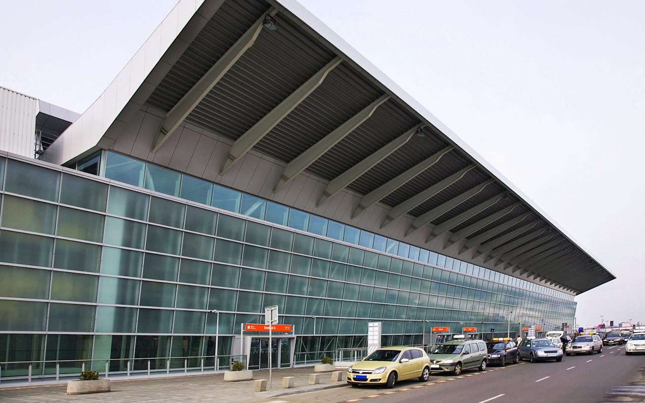 Exterior view of Warsaw Chopin Airport terminal with parked cars.