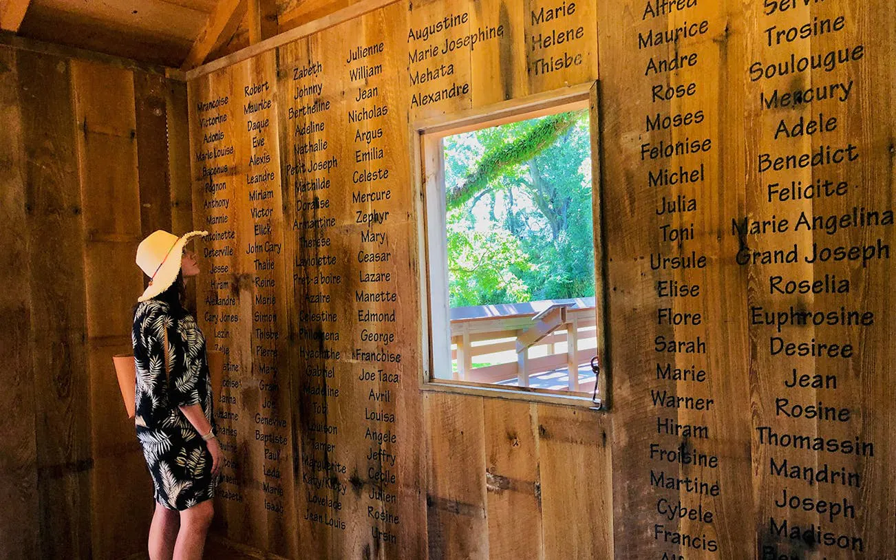 Visitor observing names on a wooden wall at Oak Alley Plantation, New Orleans.