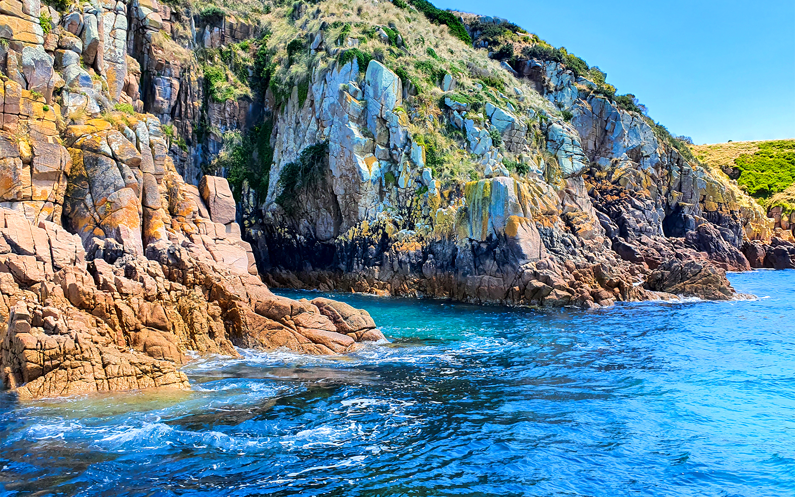 Rocky cliffs and blue ocean at Cape Woolamai, Phillip Island cruise.