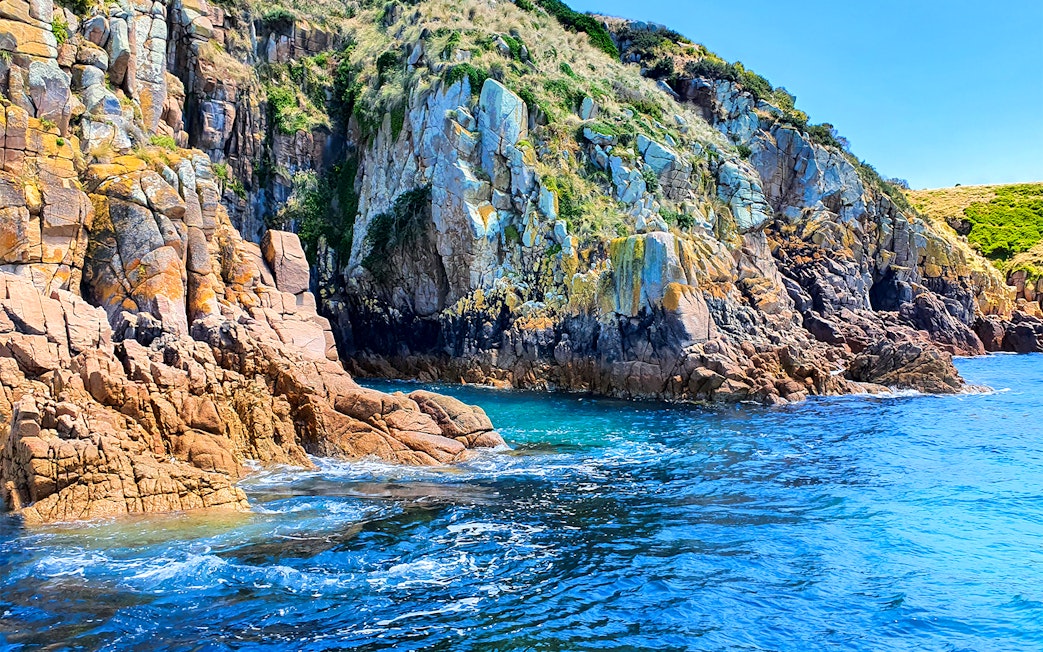 Rocky cliffs and blue ocean at Cape Woolamai, Phillip Island cruise.