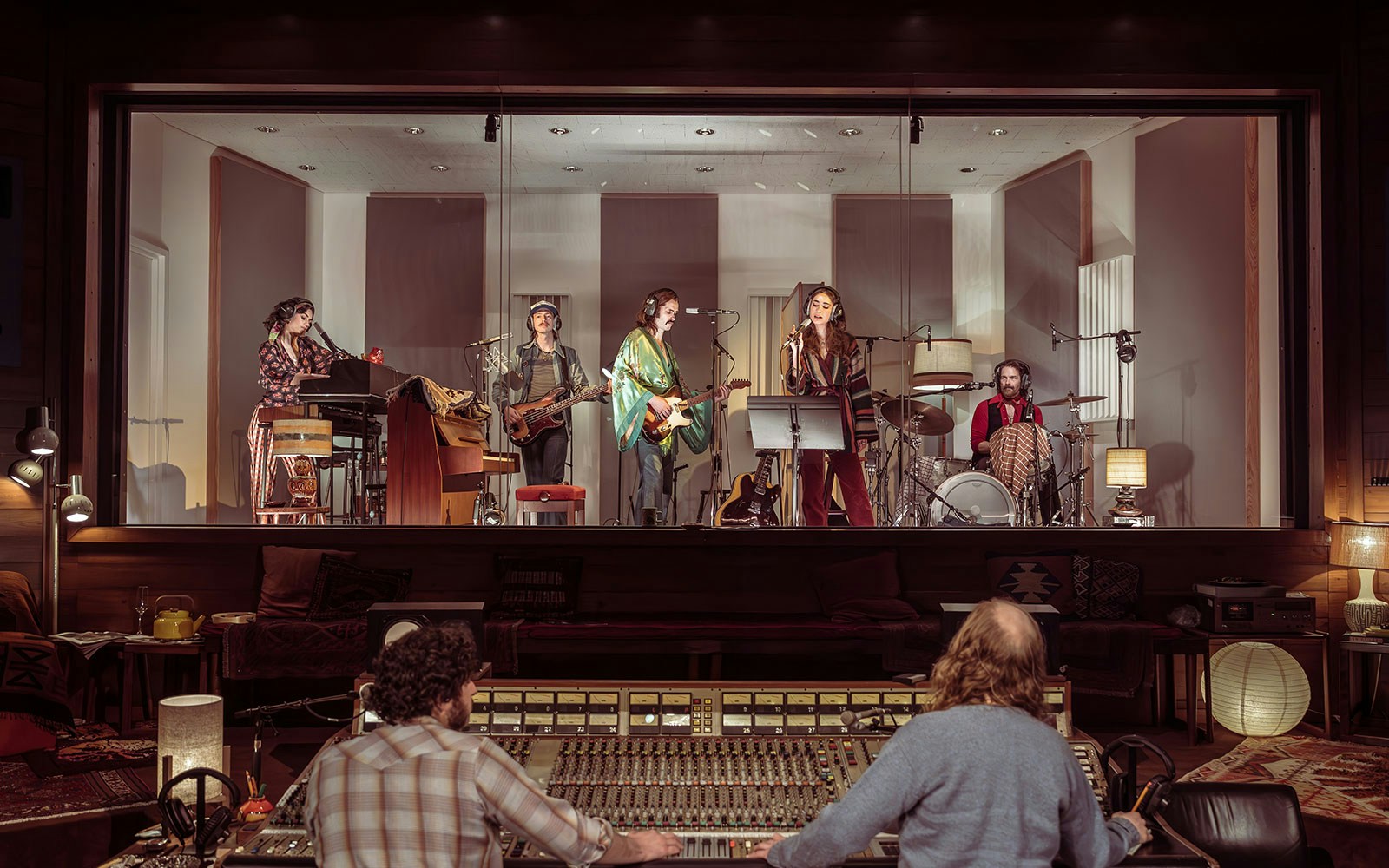 Band recording in a studio with sound engineers at a mixing console, related to Stereophonic.