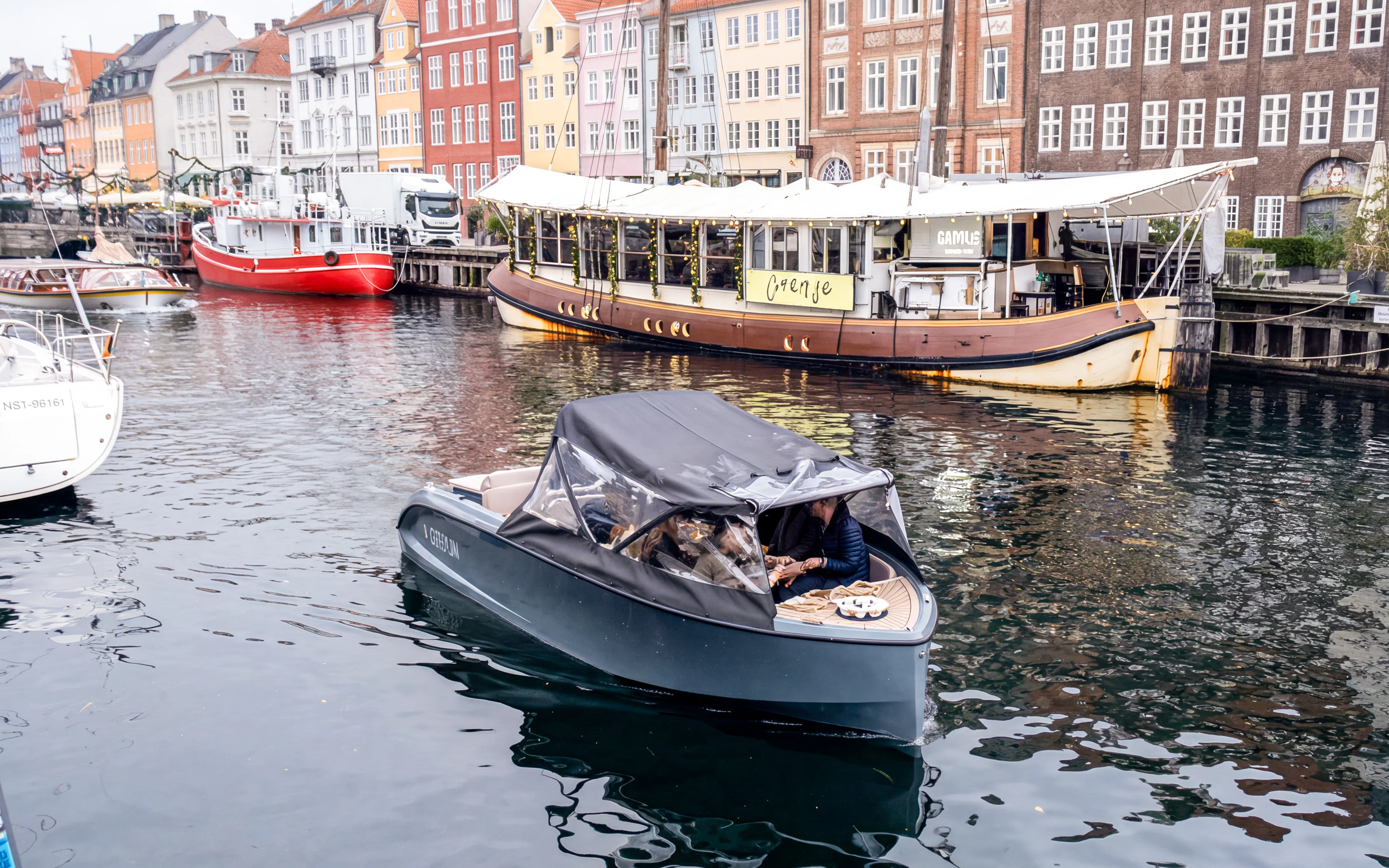Canal boat cruising past colorful buildings in Copenhagen.