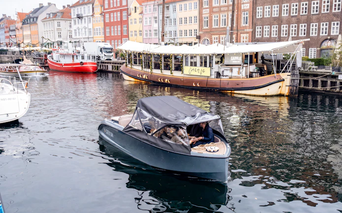 Canal boat cruising past colorful buildings in Copenhagen.