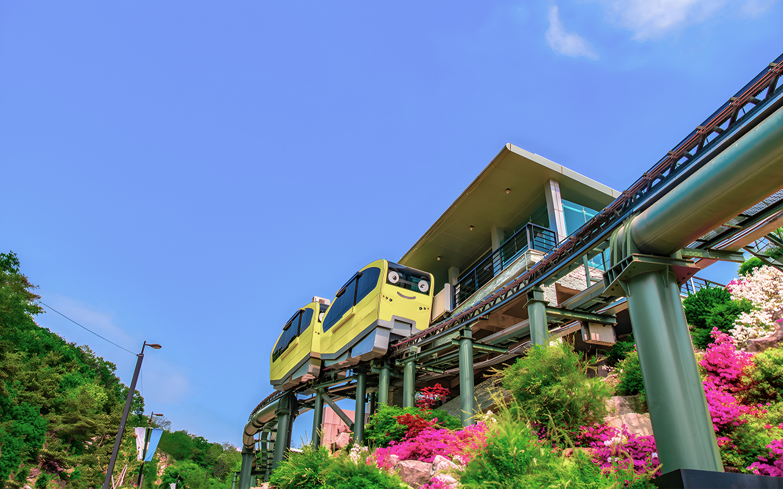 Yellow monorail at Pocheon Art Valley station, surrounded by colorful flowers.