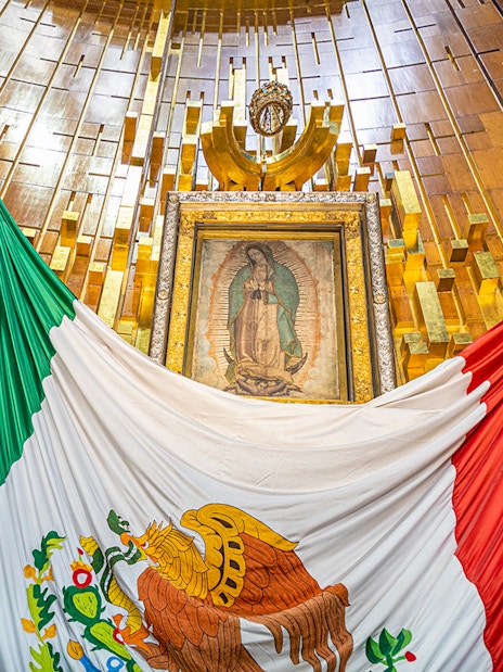 Our Lady of Guadalupe image inside Basilica of Guadalupe with Mexican flag.