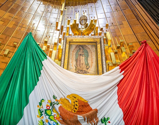 Our Lady of Guadalupe image inside Basilica of Guadalupe with Mexican flag.