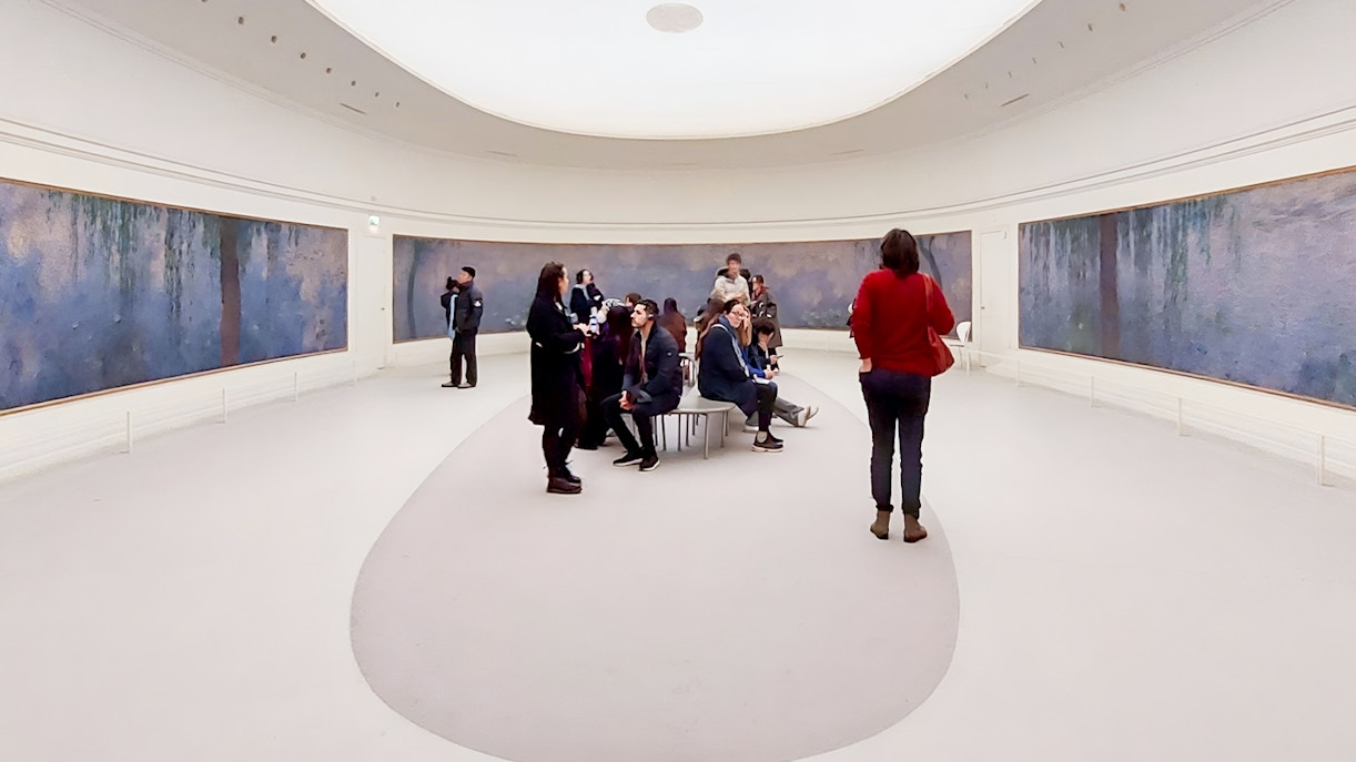 Visitors exploring art exhibits at Orangerie Museum, Paris.
