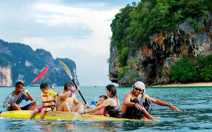 Kayaking group exploring Phang Nga Bay's limestone cliffs, Thailand.