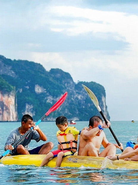 Kayaking group exploring Phang Nga Bay's limestone cliffs, Thailand.