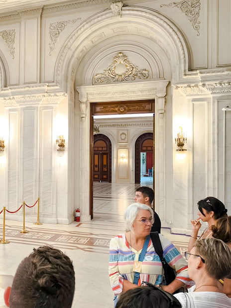 Guide leading a tour inside the ornate interior of the Palace of Parliament.