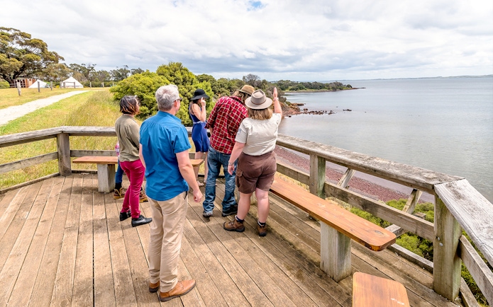 Ranger guiding visitors on a scenic trail at Churchill Island overlooking the water.