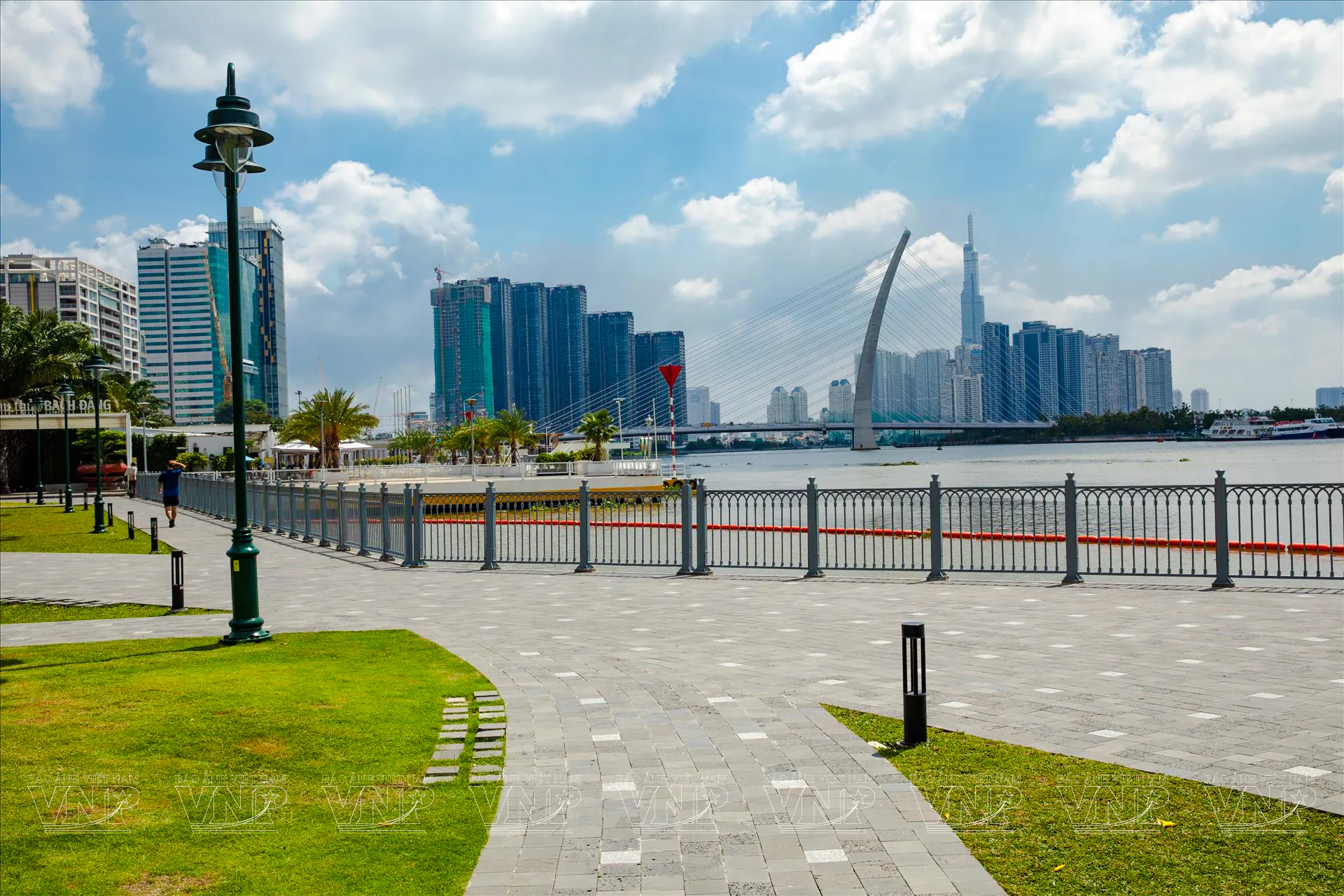 Riverside promenade with city skyline and bridge in Ho Chi Minh City, Vietnam.