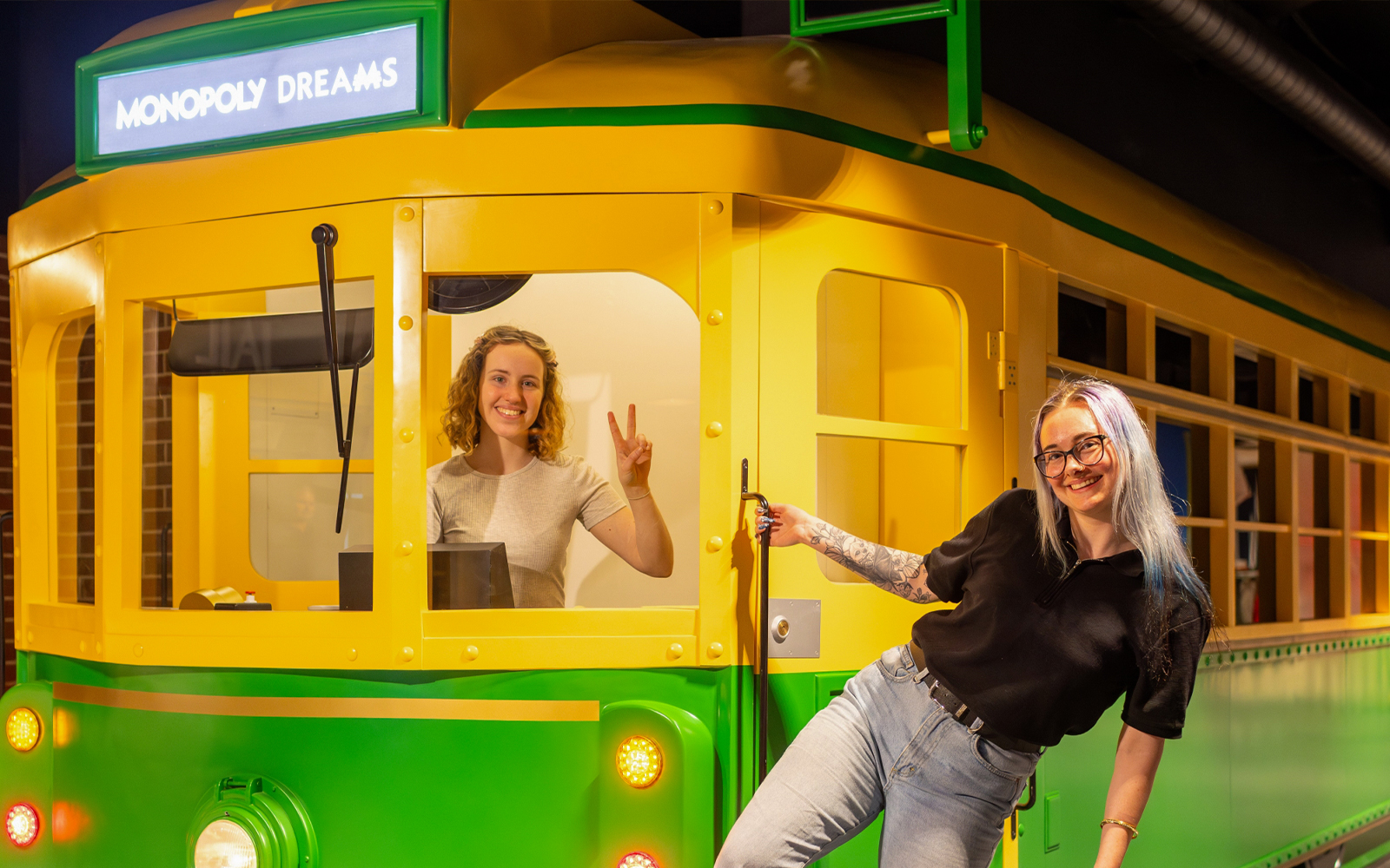 Monopoly Dreams Melbourne tram exhibit with two smiling visitors.