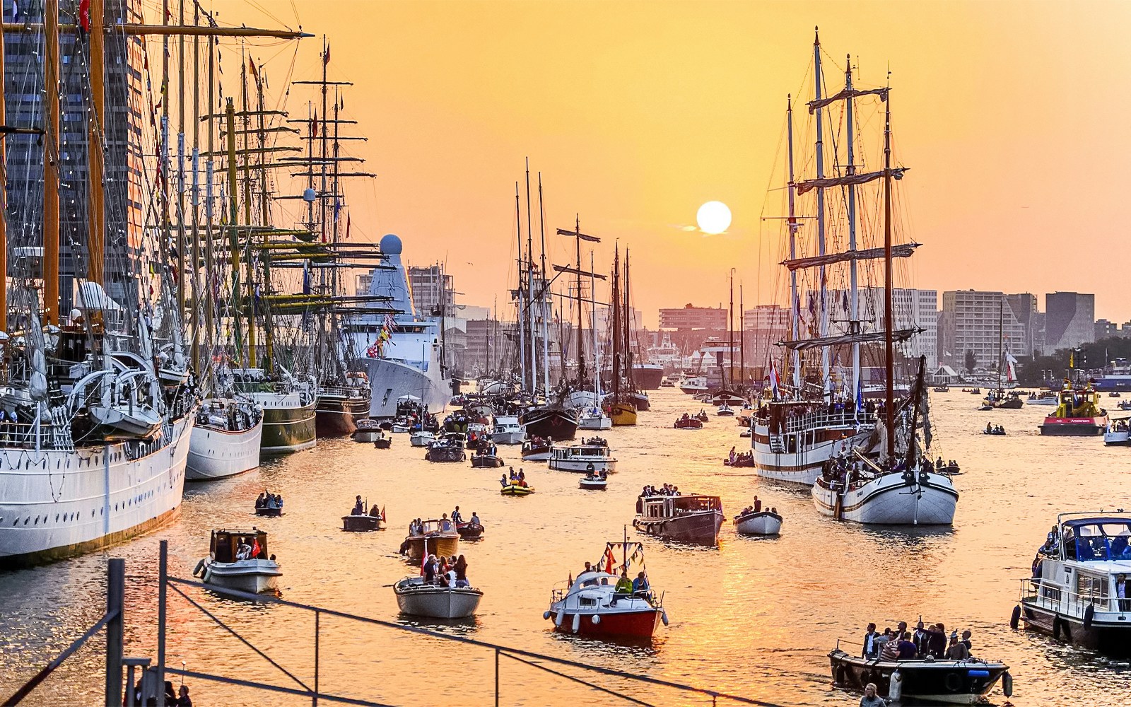 Boats sailing in Amsterdam during the evening with city lights reflecting on the water.