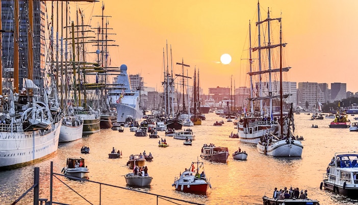 Boats sailing in Amsterdam during the evening with city lights reflecting on the water.