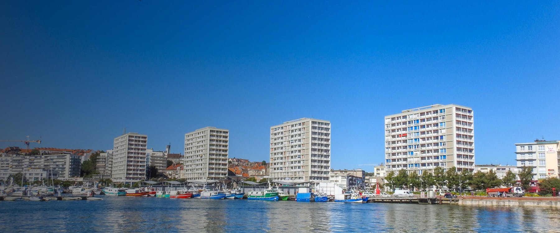 Harbor with colorful boats and modern buildings in Boulogne sur Mer, France.