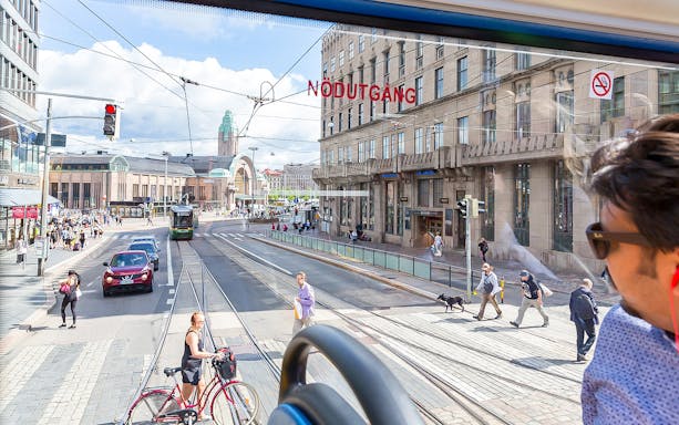 Helsinki city view from a hop-on hop-off bus, featuring the central railway station and street activity.