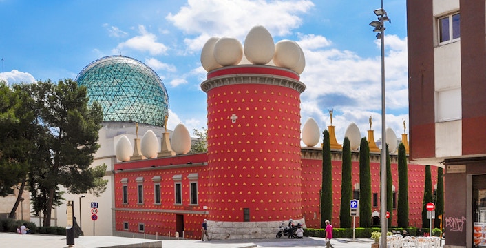 Dalí House Museum in Figueres with red facade and egg sculptures, view from the square.
