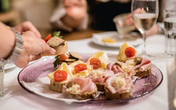 Assorted appetizers on a plate with wine during a guided tasting in hidden wine cellars.