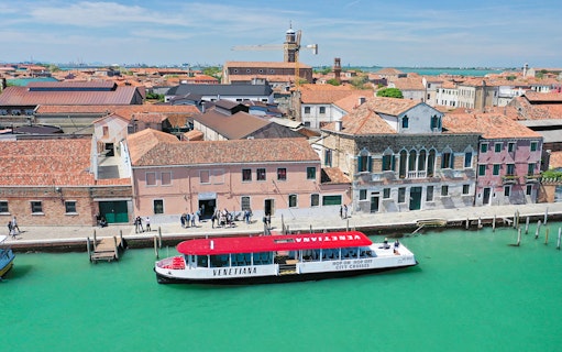 Venice hop-on hop-off boat near historic buildings along a canal.