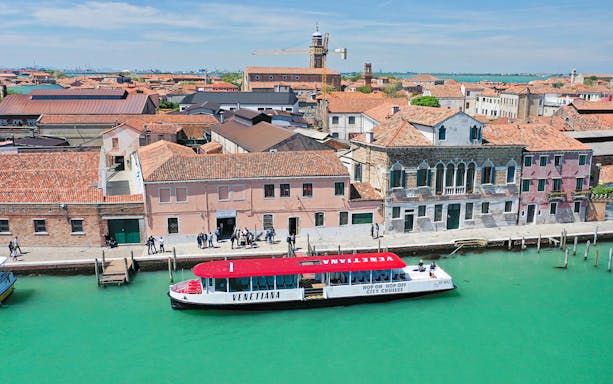 Venice hop-on hop-off boat near historic buildings along a canal.