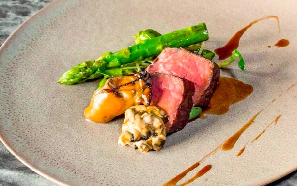 Wagyu beef slices with asparagus and sauce on a plate at Akasaka NonTitle.
