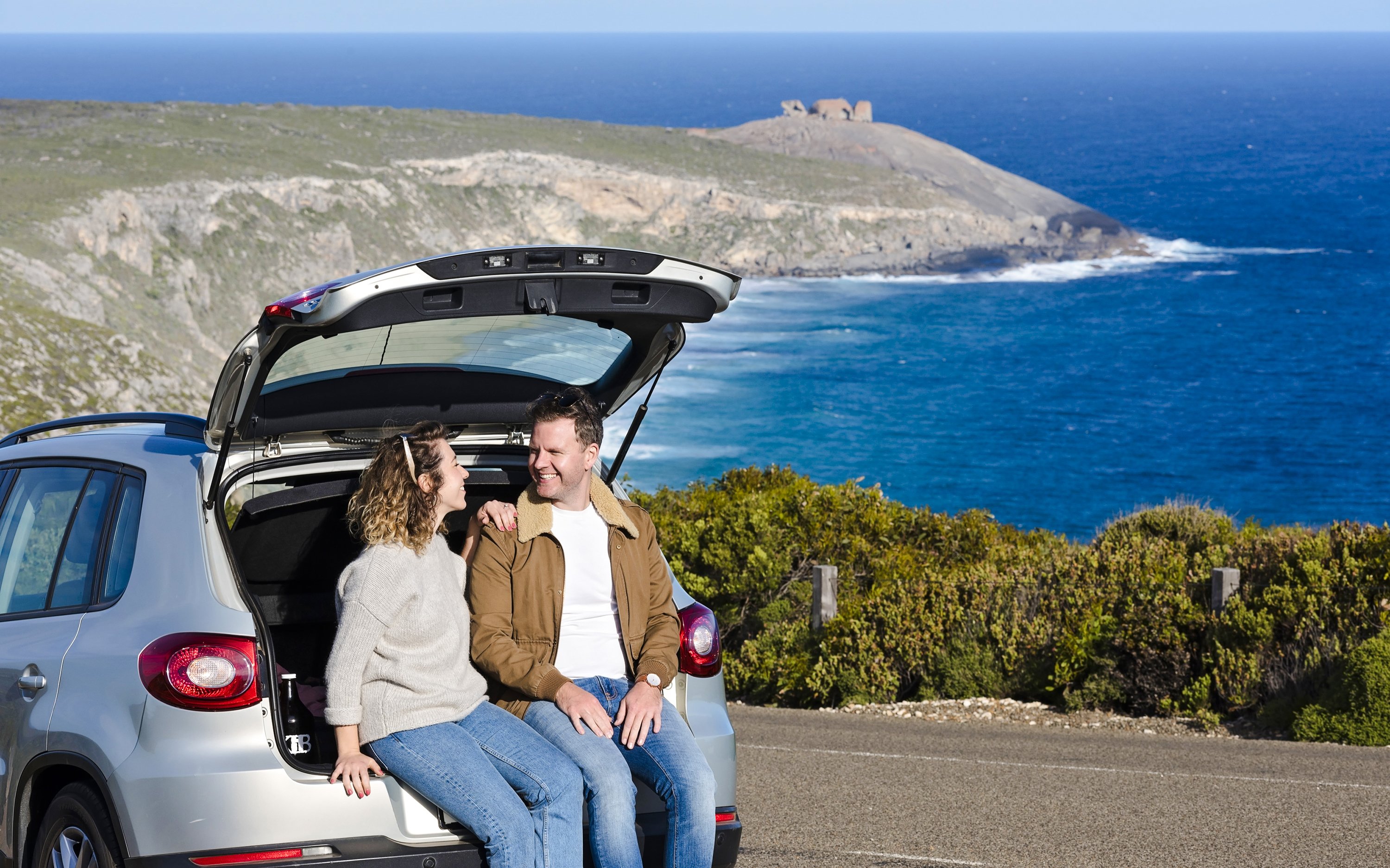 Couple sitting in car at Kangaroo Island with ocean view in background.