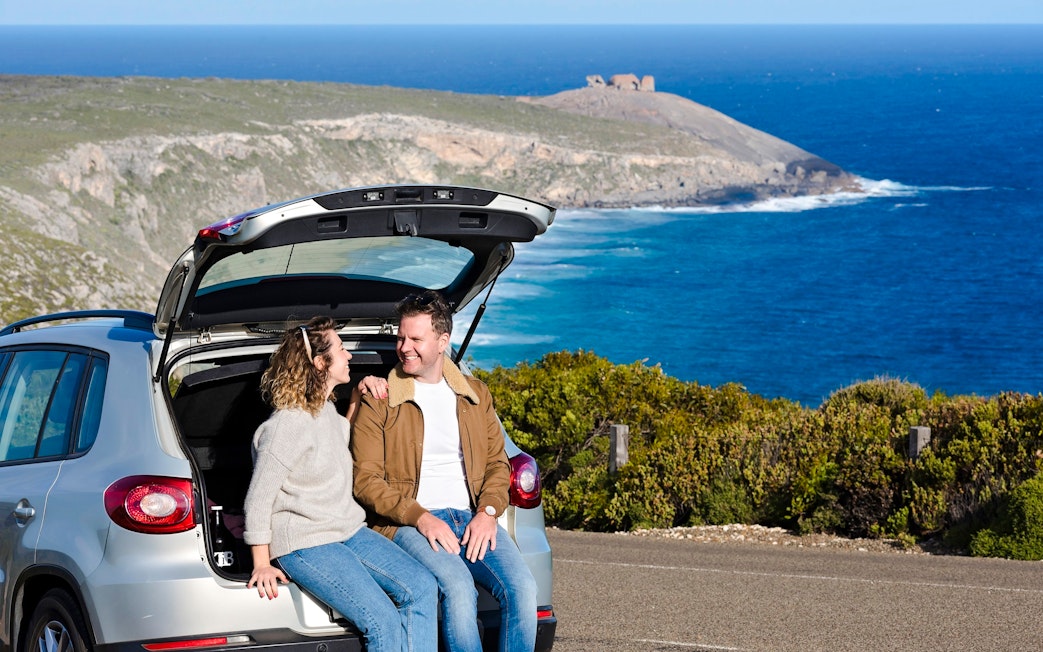 Couple sitting in car at Kangaroo Island with ocean view in background.