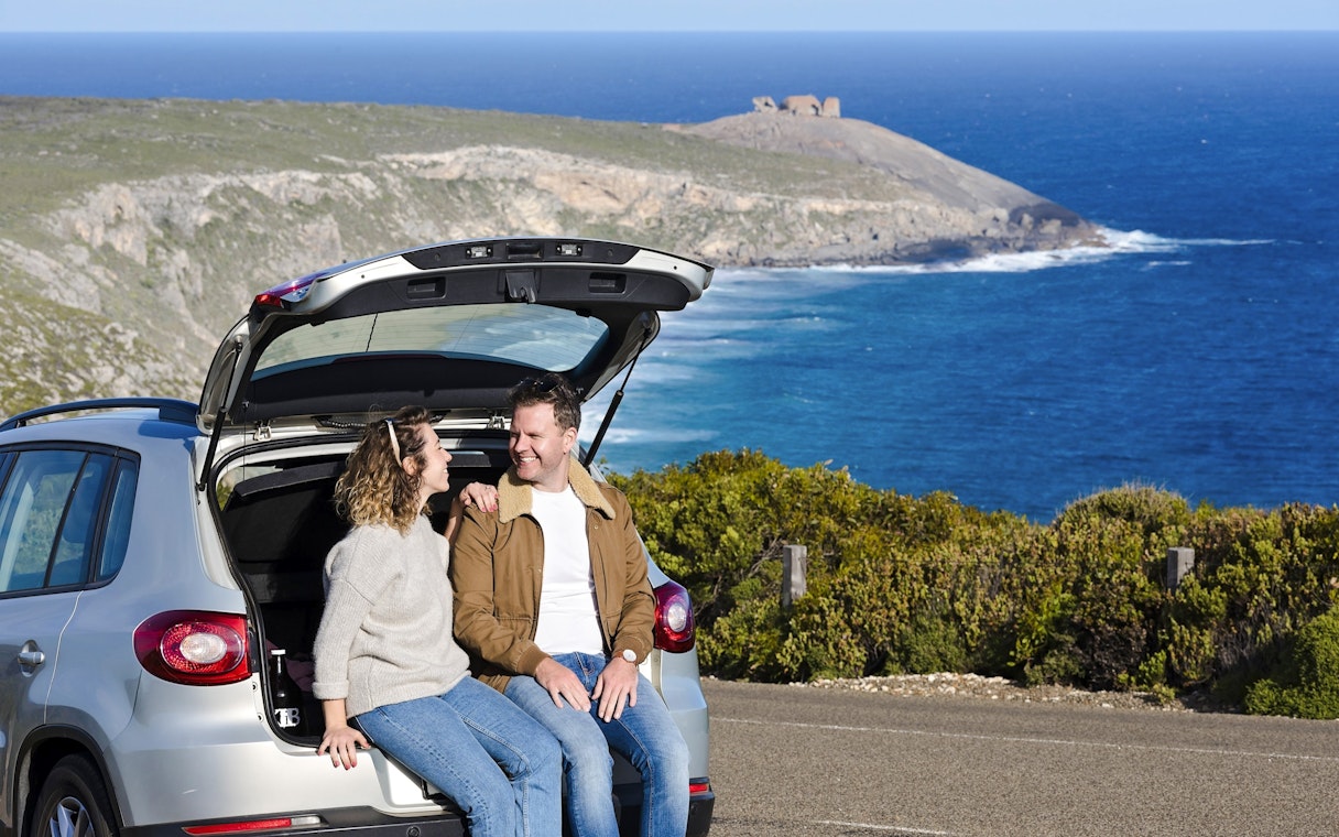 Couple sitting in car at Kangaroo Island with ocean view in background.
