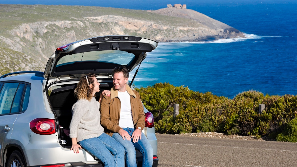 Couple sitting in car at Kangaroo Island with ocean view in background.