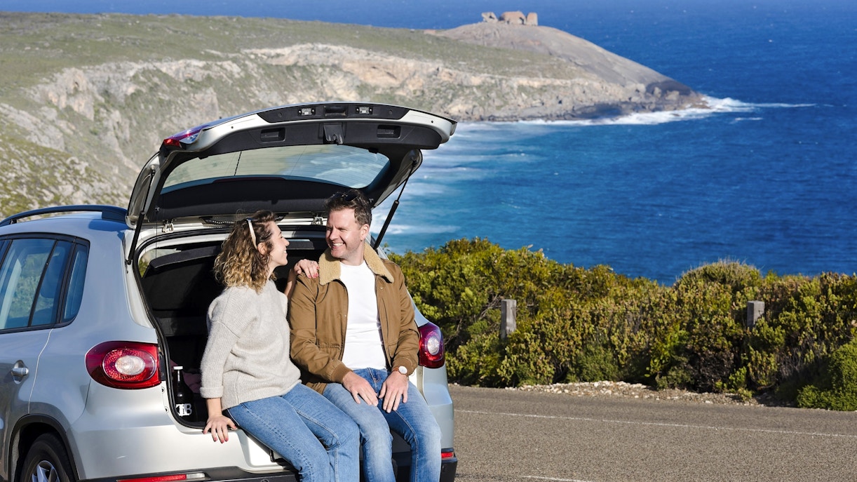 Couple sitting in car at Kangaroo Island with ocean view in background.
