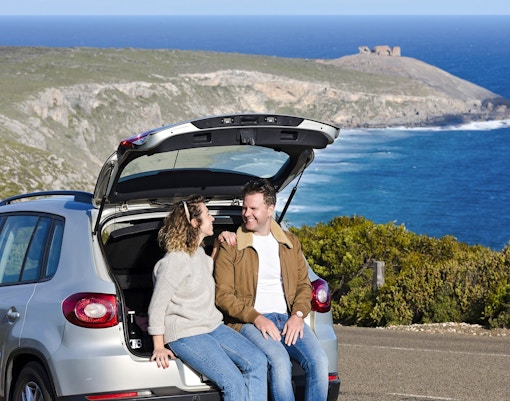 Couple sitting in car at Kangaroo Island with ocean view in background.