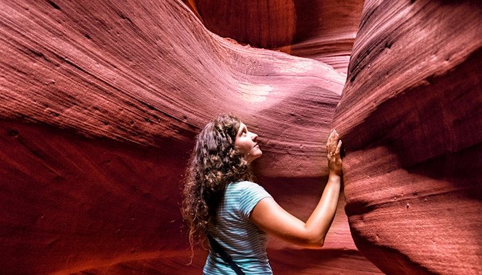 Young woman exploring the sandstone formations of Antelope Canyon.