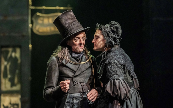 Actors in period costumes performing a scene from "Oliver" on stage.