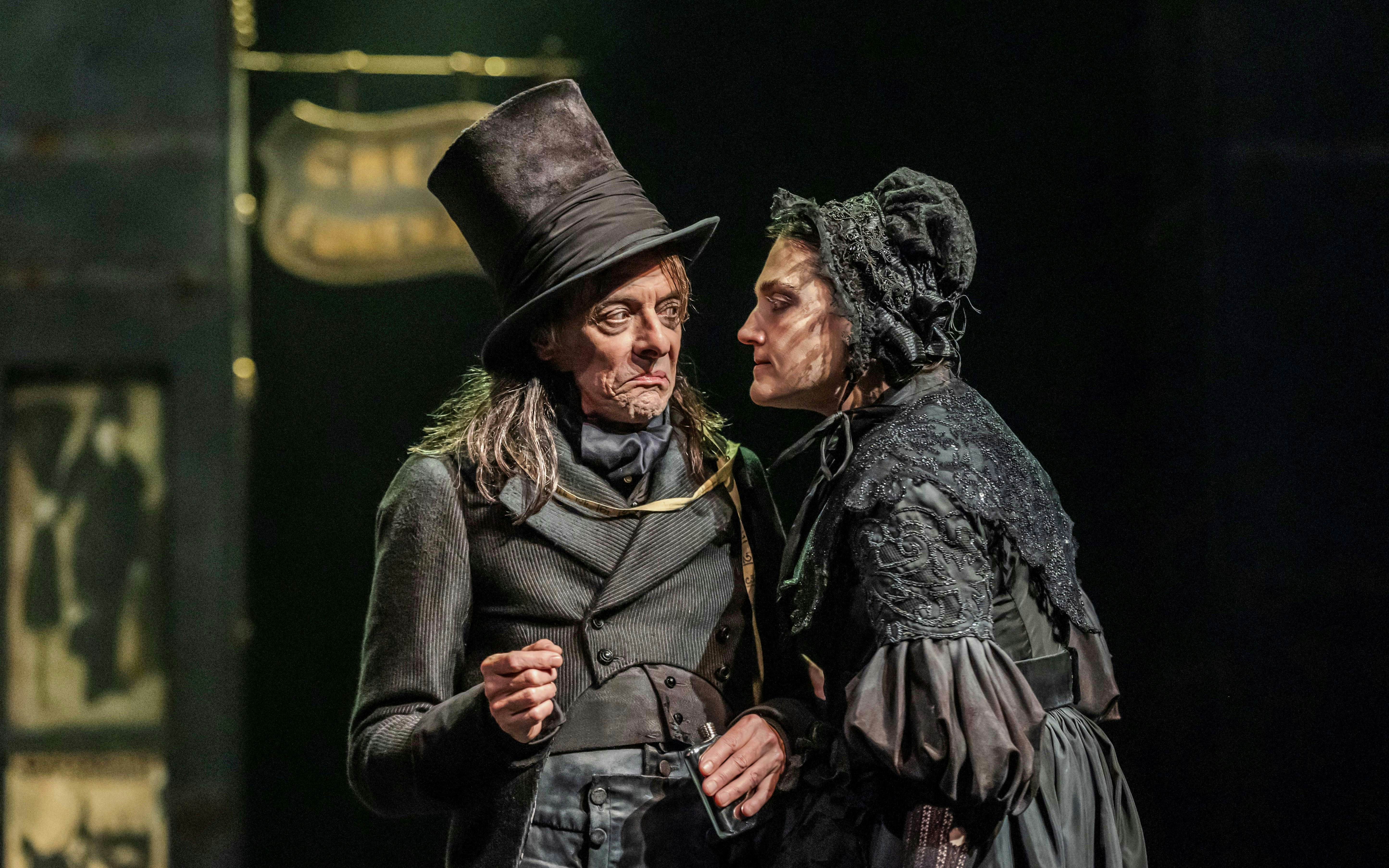 Actors in period costumes performing a scene from "Oliver" on stage.