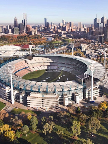 Aerial view of Melbourne Cricket Ground with city skyline in the background.