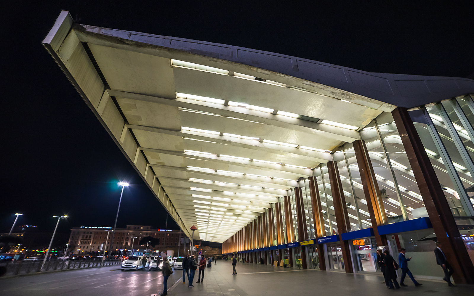 Roma Termini station entrance at night with people walking and taxis waiting.