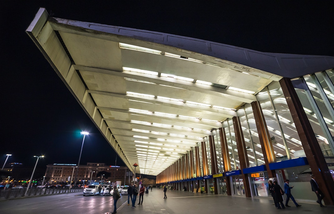 Roma Termini station entrance at night with people walking and taxis waiting.