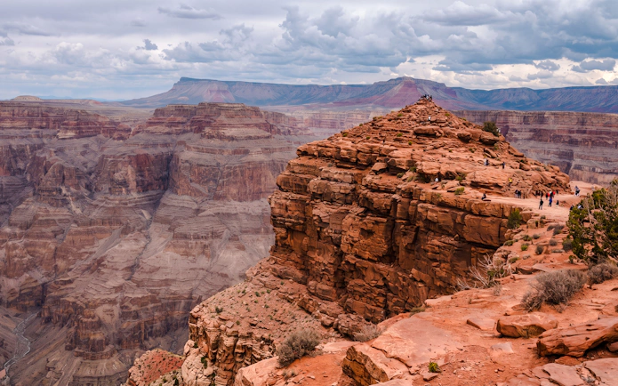 Helicopter landing site on rocky ledge inside Grand Canyon West with tourists exploring.