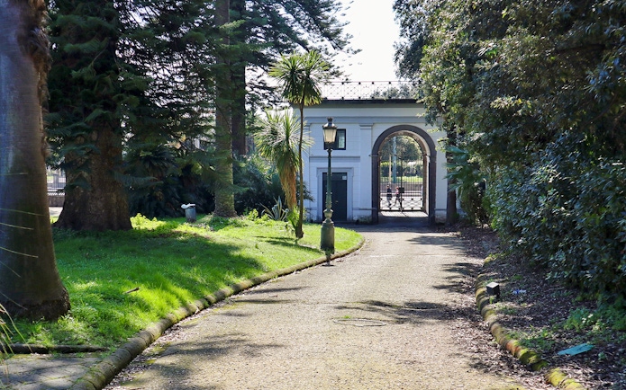 Villa Pignatelli entrance with archway and surrounding greenery in Naples, Italy.