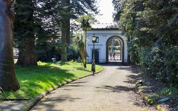 Villa Pignatelli entrance with archway and surrounding greenery in Naples, Italy.