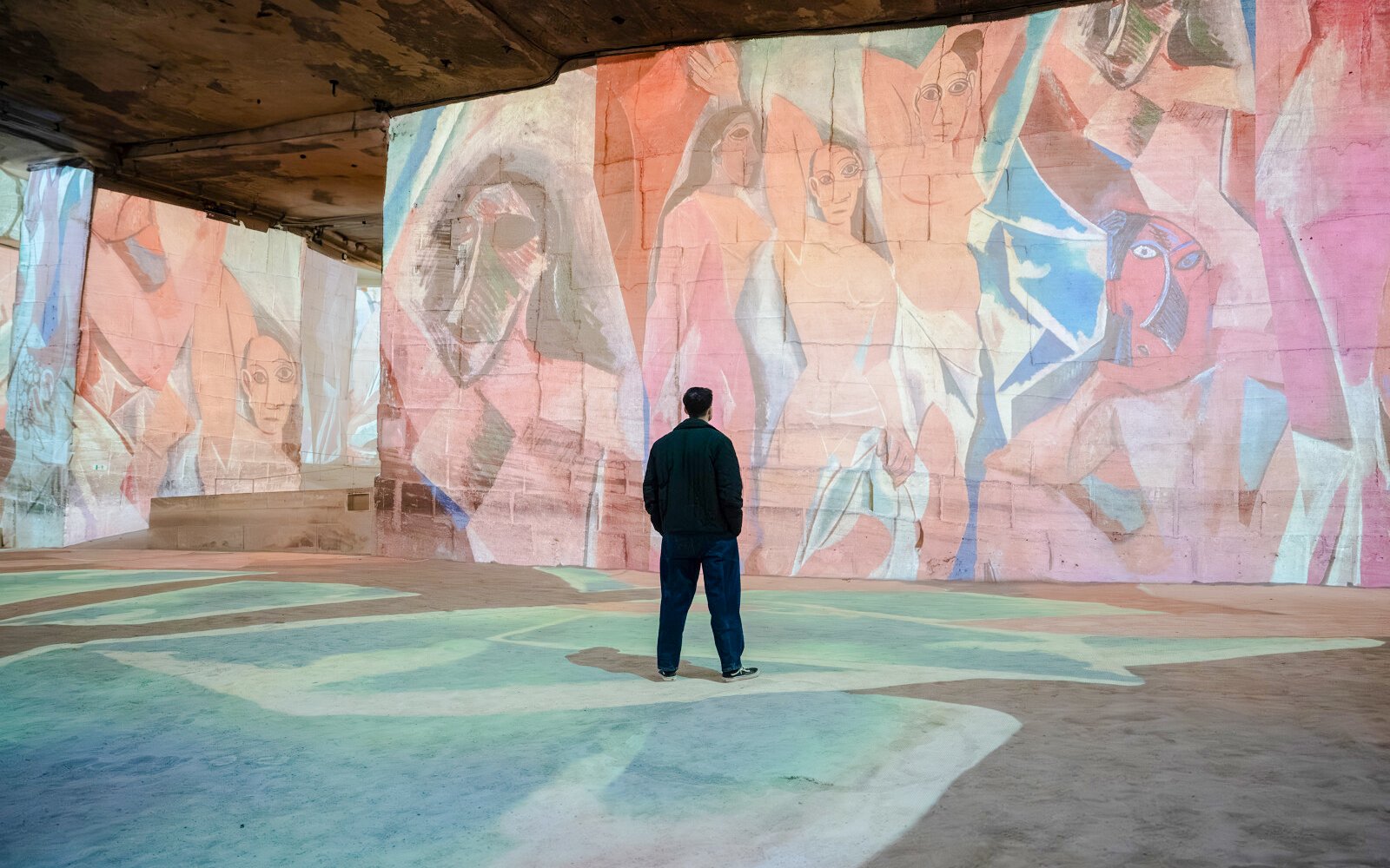 Man viewing Picasso artwork projection at Carrières des Lumières exhibit.