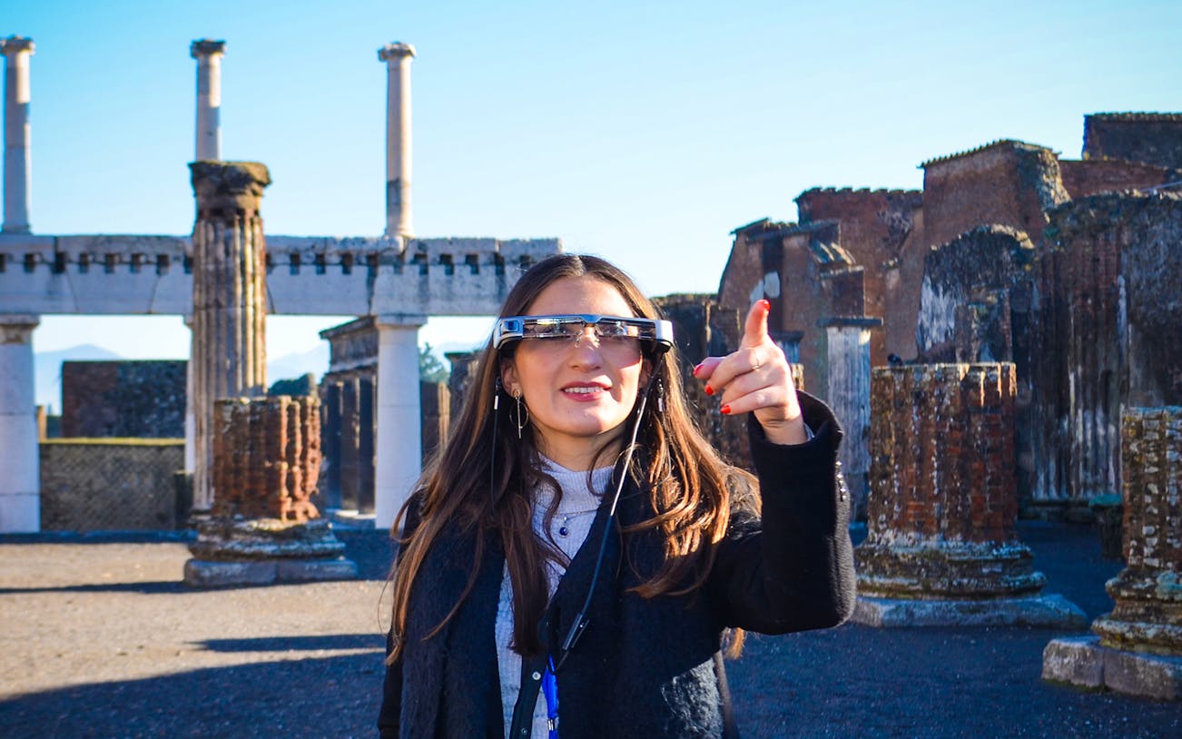 Visitor using augmented reality glasses at Pompeii ruins, Italy.
