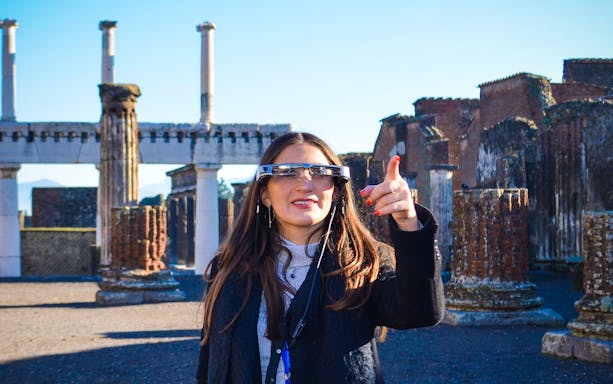 Visitor using augmented reality glasses at Pompeii ruins, Italy.