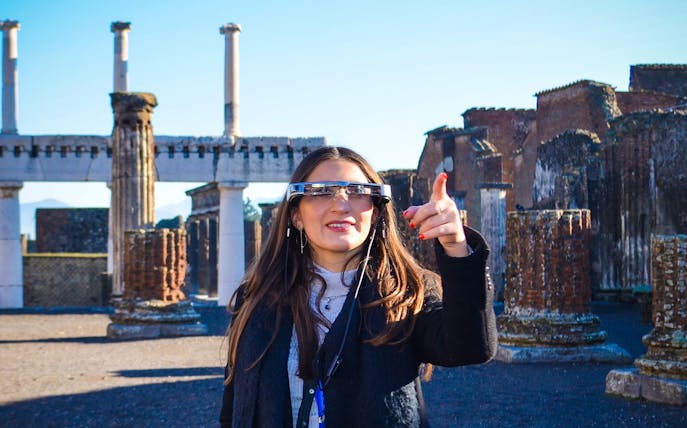 Visitor using augmented reality glasses at Pompeii ruins, Italy.