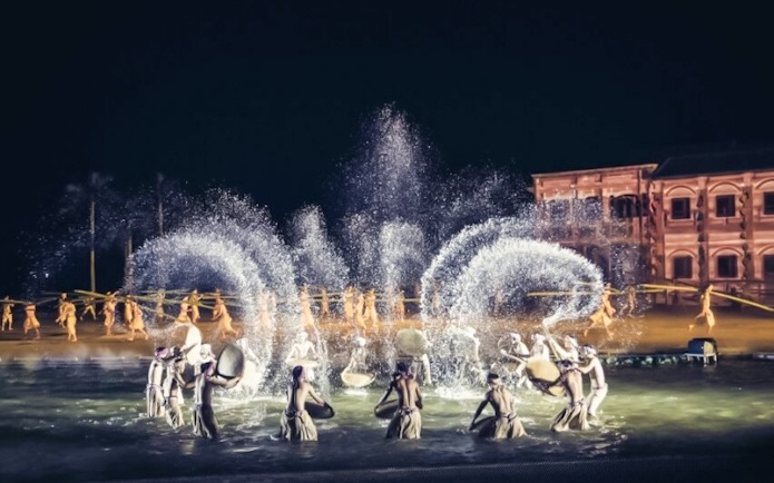 Performers in traditional attire during Hoi An Memories Show with water effects.